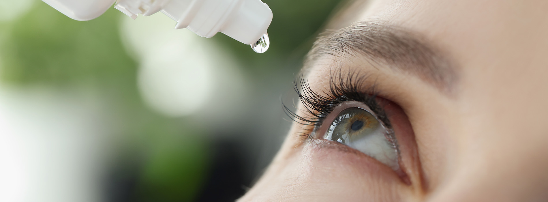 The image shows a close-up of a person s eye with a dropper containing a clear liquid being held over it, suggesting an action of administering medication or care product.