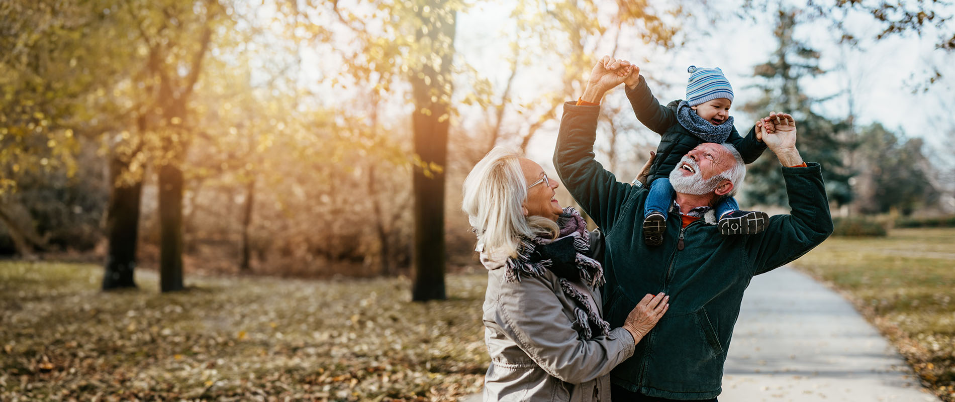 A family walking together on a sidewalk during autumn with trees lining the street.
