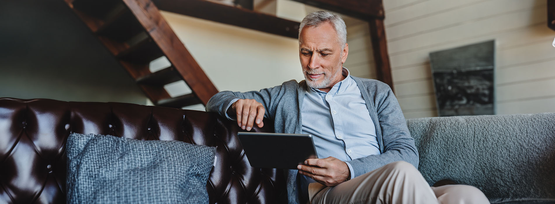 Man sitting on couch in living room, looking at cell phone.